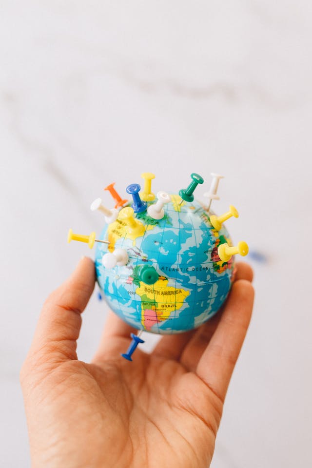 A person holding a globe with pins sticking out of it. 