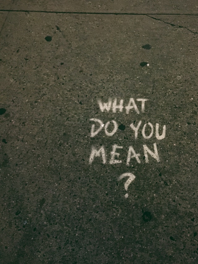 The words “what do you mean?” written on the pavement. 