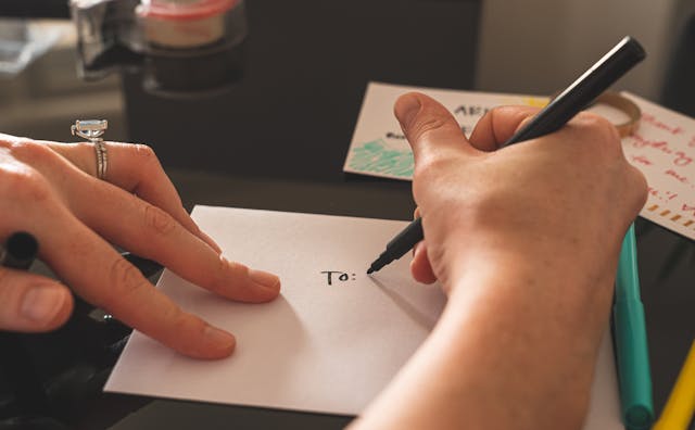 A person writing an address on a piece of paper. 