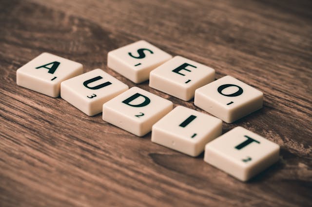 The phrase “SEO Audit” with tiles on a wooden table. 